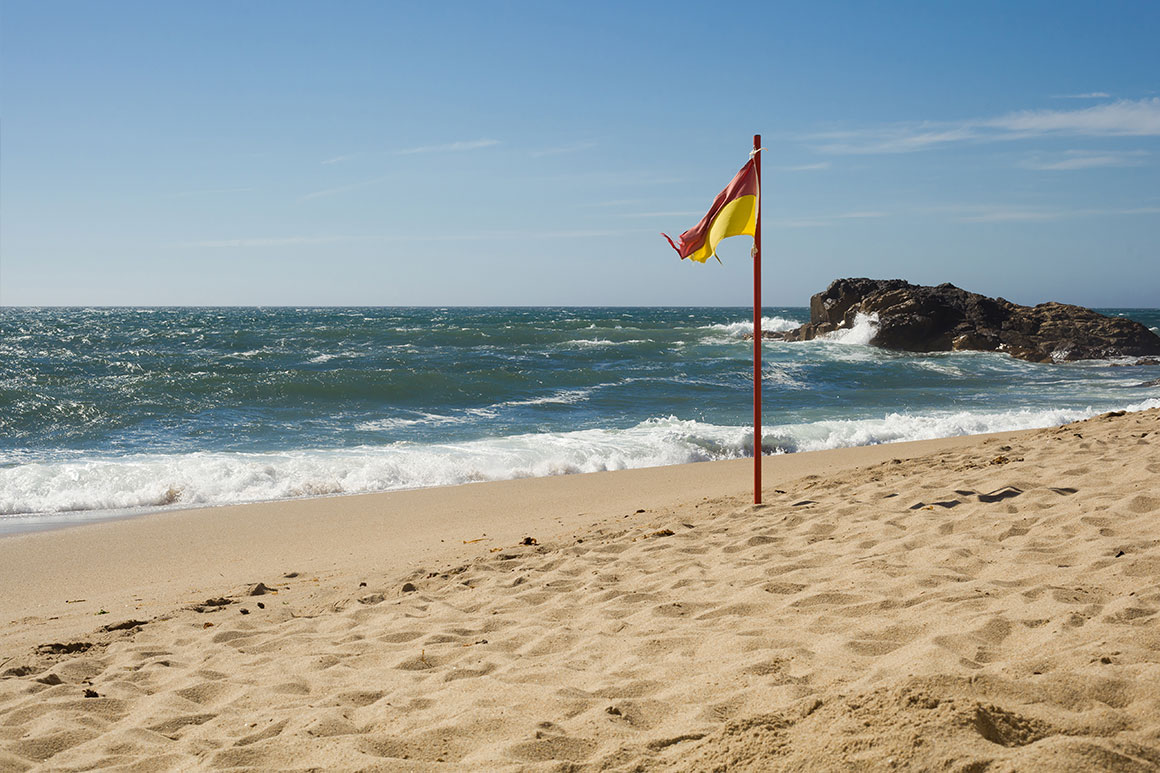 Červeno-žltá vlajka na pláži v Porte